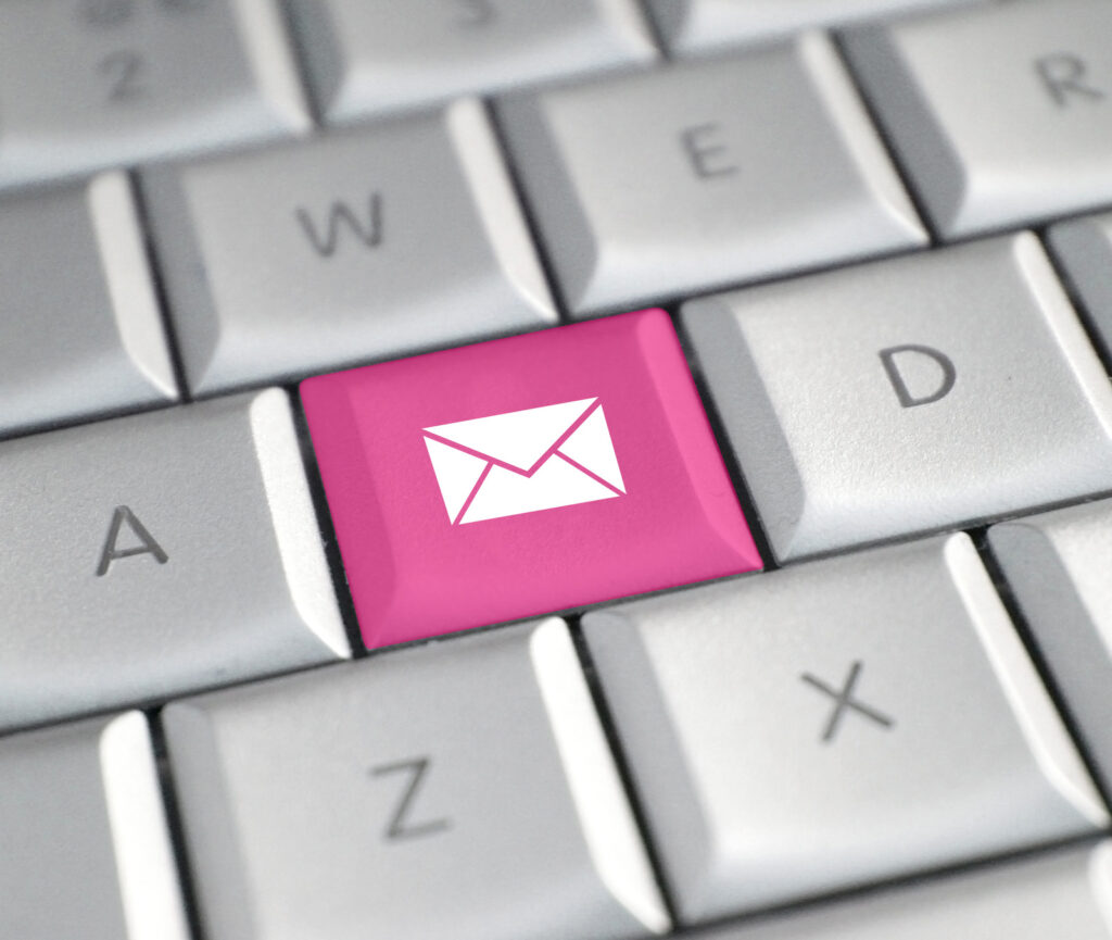 A laptop Keyboard has one of the keys replaced with a pink email icon.